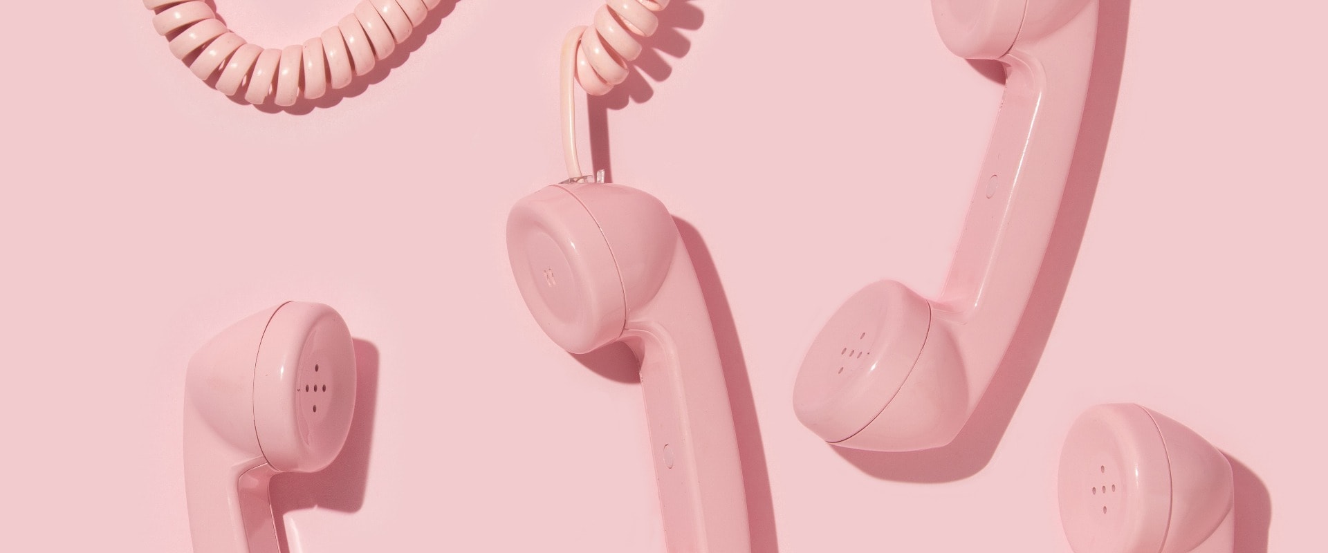 Creative layout with pink retro phone handsets on pastel pink background. 80s or 90s retro fashion aesthetic telephone concept. Minimal romantic handset idea. Valentines day idea.